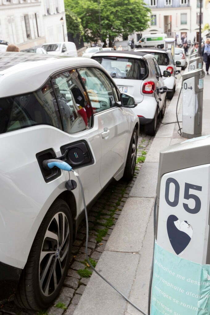 Advantages of Electric Cars: Why They're Good for the Environment. Image of a row of Electric Vehicles charging on a public street.