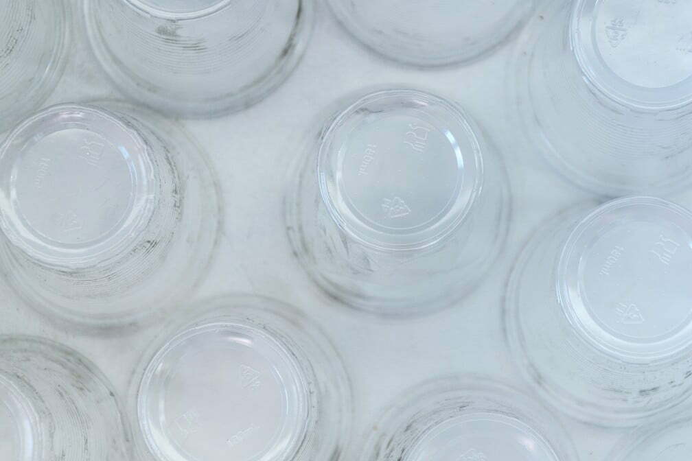dirty empty plastic glasses on a white background top view close up abstract backdrop of New Technique Turns Plastic Waste Back Into Refinery-Quality Oil