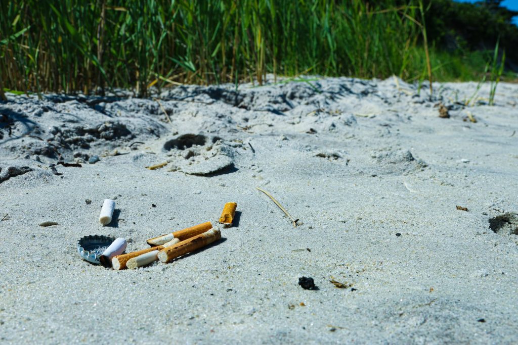 Image of cigarette butts on a beac. Spain Cigarette Butt Law places a Bounty on Butts.