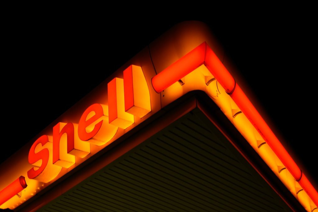 Shell Oil Sued by Shareholders for Poor Climate Action Performance. Image of a Shell gas station sign at night. 