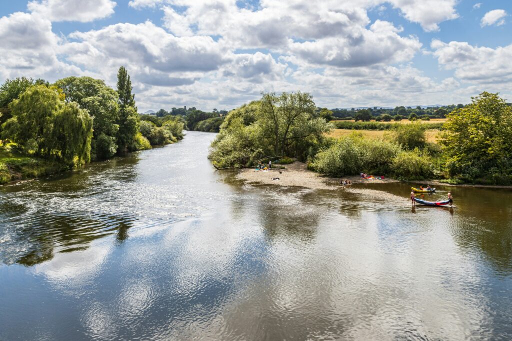 A river flowing freely where a small dam or weir has been removed, with natural banks and vegetation.